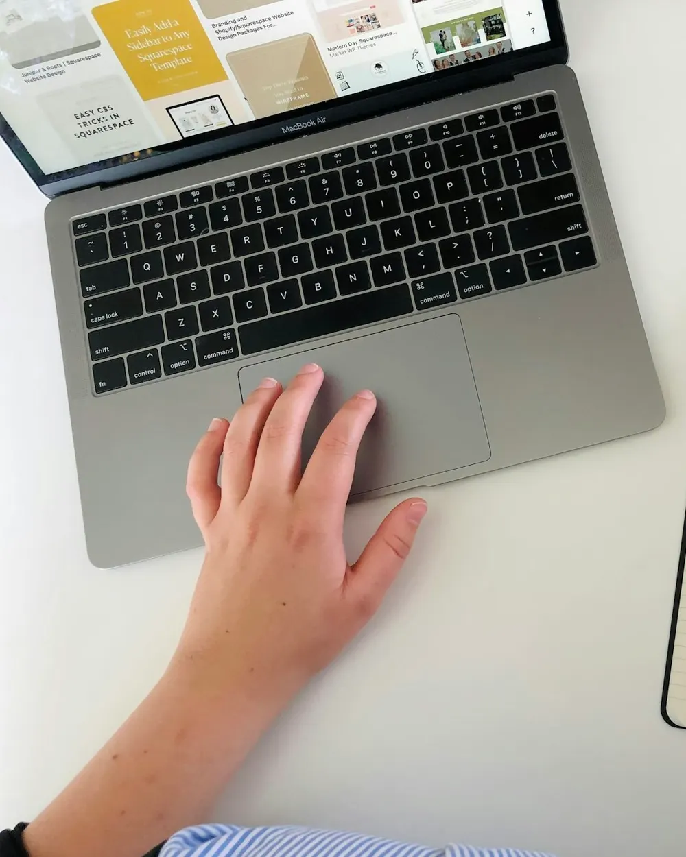 Manos escribiendo en una libreta junto a una laptop